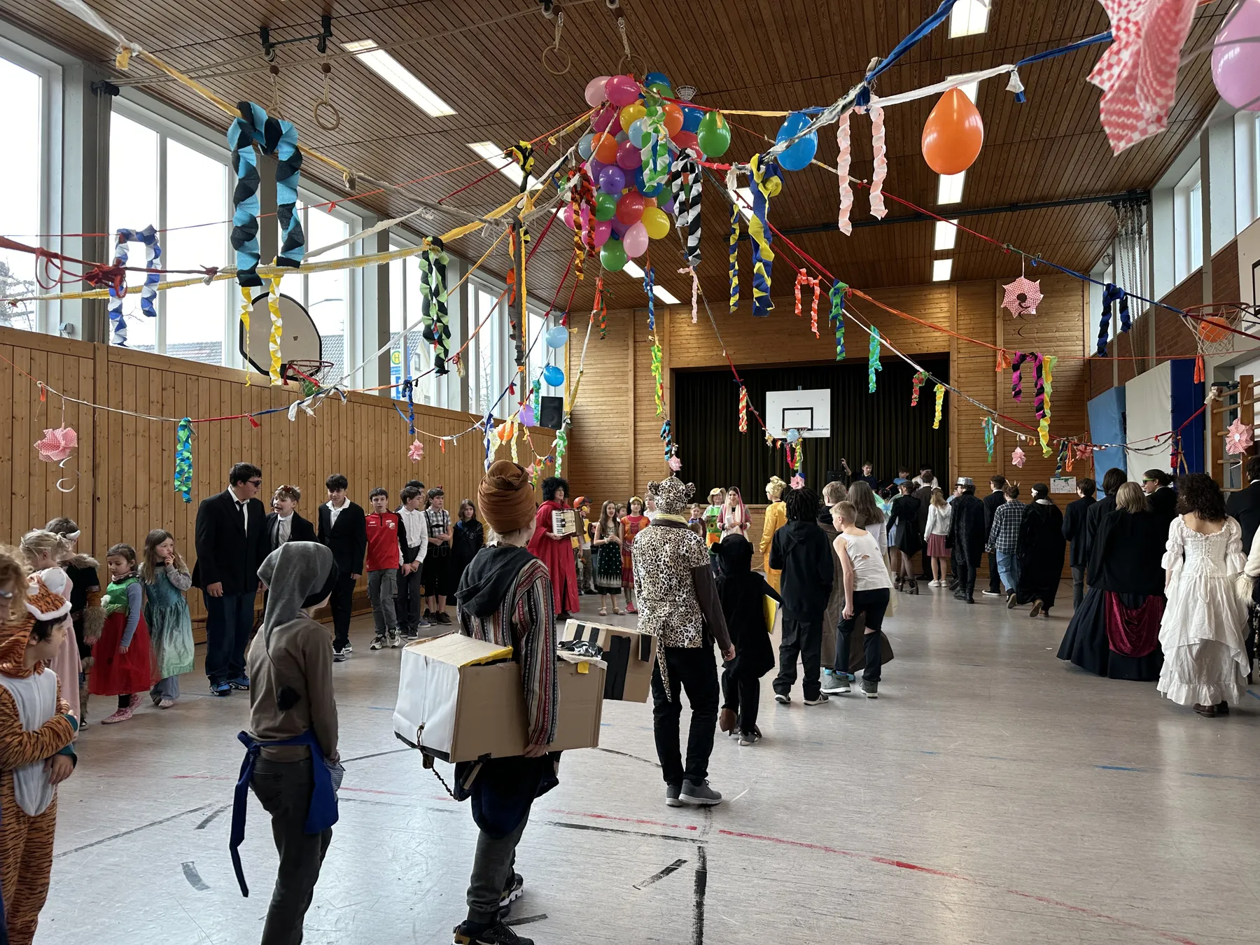 Verkleidete Kinder feiern Fasching in der geschmückten Turnhalle